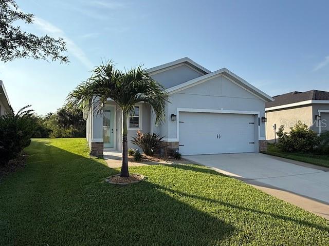 10962 High Noon Trl, Parrish, FL 34219 - ranch-style house featuring an attached garage, a front lawn, driveway, stucco siding, and stone siding