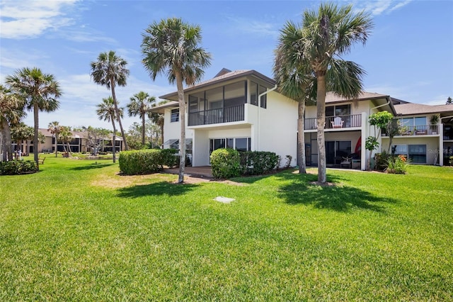 rear view of house featuring stucco siding and a lawn