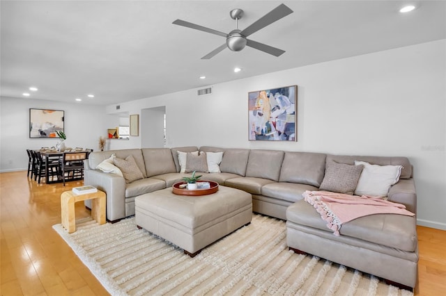 living room with recessed lighting, light wood-style flooring, a ceiling fan, and baseboards