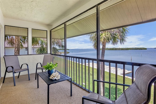 sunroom / solarium with a water view, plenty of natural light, a textured ceiling, and carpet floors