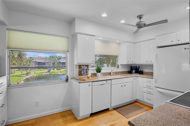 kitchen featuring white appliances, light wood-style flooring, a ceiling fan, white cabinetry, and a sink