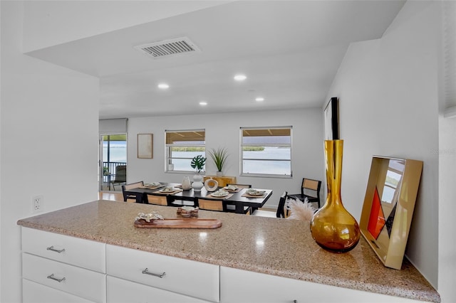 kitchen featuring light stone counters, recessed lighting, and white cabinets