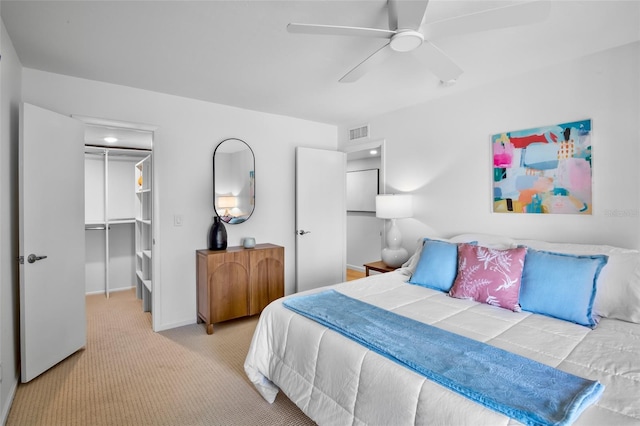 bedroom with carpet floors, a walk in closet, a closet, baseboards, and a ceiling fan