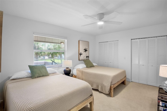 bedroom with two closets, a ceiling fan, and light colored carpet