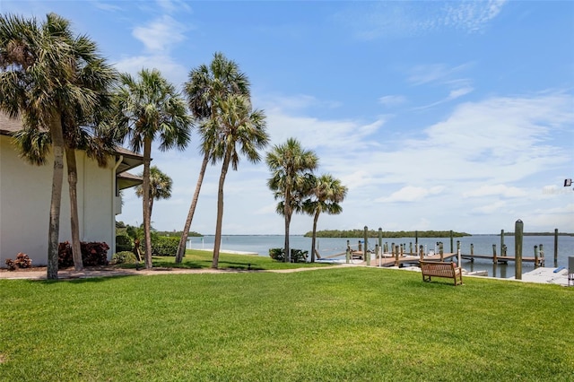 view of green lawn with a boat dock and a water view