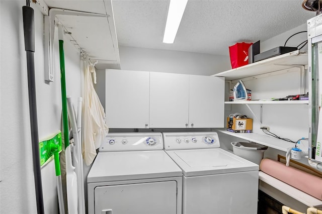 clothes washing area featuring independent washer and dryer, a textured ceiling, and cabinet space