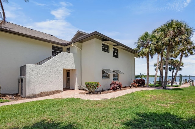 back of property featuring stucco siding, a yard, and a water view