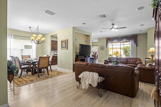 4402 Natures Reach Ter, Parrish, FL 34219 - living room with a chandelier, light wood finished floors, baseboards, a ceiling fan, and a textured ceiling