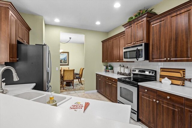 4402 Natures Reach Ter, Parrish, FL 34219 - kitchen with stainless steel appliances, decorative backsplash, light countertops, a sink, and recessed lighting