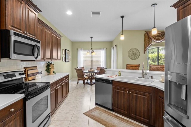 4402 Natures Reach Ter, Parrish, FL 34219 - kitchen featuring appliances with stainless steel finishes, a sink, hanging light fixtures, light countertops, and decorative backsplash