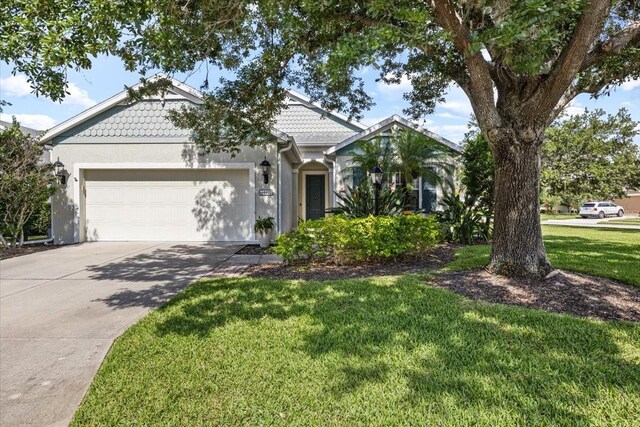 4402 Natures Reach Ter, Parrish, FL 34219 - victorian house featuring a garage, a front yard, driveway, and stucco siding