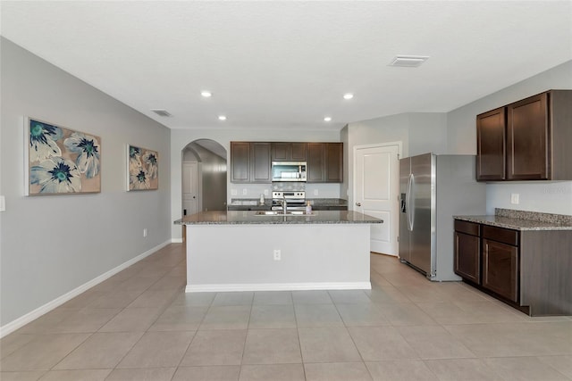 12712 Dusty Trail Dr, Sarasota, FL 34238 - kitchen with appliances with stainless steel finishes, arched walkways, recessed lighting, dark stone counters, and dark brown cabinets