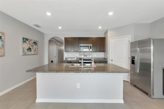 12712 Dusty Trail Dr, Sarasota, FL 34238 - kitchen featuring stainless steel appliances, arched walkways, a sink, a center island with sink, and dark brown cabinets