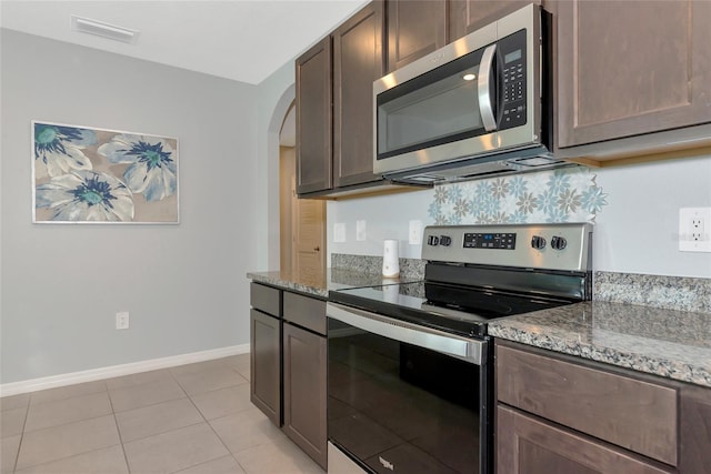 12712 Dusty Trail Dr, Sarasota, FL 34238 - kitchen with stainless steel appliances, arched walkways, stone counters, and baseboards