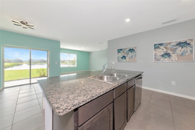 12712 Dusty Trail Dr, Sarasota, FL 34238 - kitchen featuring a sink, light tile patterned floors, an island with sink, a water view, and light stone counters