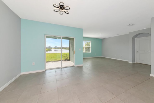 12712 Dusty Trail Dr, Sarasota, FL 34238 - spare room featuring light tile patterned floors, a chandelier, a water view, and baseboards