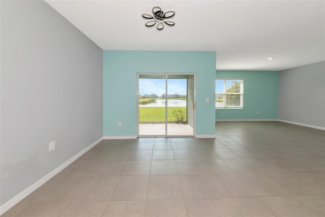 12712 Dusty Trail Dr, Sarasota, FL 34238 - empty room featuring a chandelier, a water view, light tile patterned floors, and baseboards