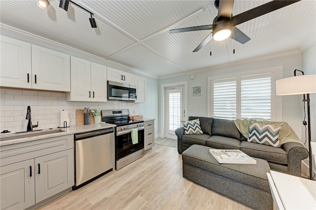301 Highland Ave Unit 3, Bradenton Beach, FL 34217 - kitchen with stainless steel appliances, backsplash, a sink, ornamental molding, and light wood-style floors