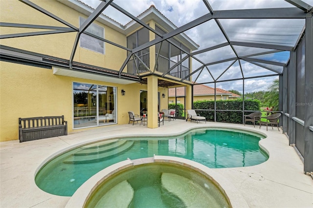 view of swimming pool with a patio, a pool with connected hot tub, and glass enclosure