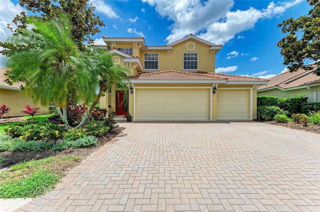 mediterranean / spanish house with stucco siding, decorative driveway, a tiled roof, and an attached garage