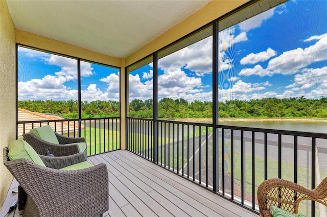 sunroom featuring a water view and view of wooded area