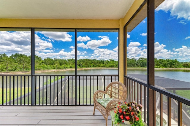 unfurnished sunroom featuring a water view and view of scattered trees