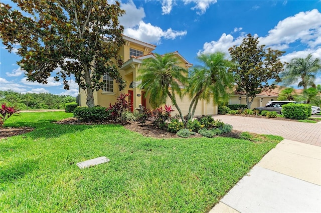 mediterranean / spanish house featuring decorative driveway, stucco siding, a front yard, and a garage