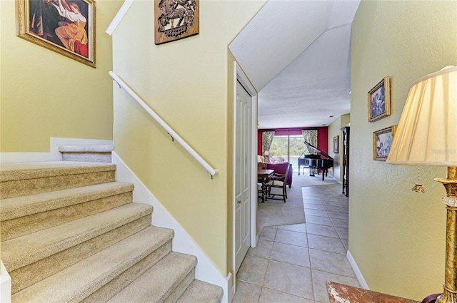 stairs with tile patterned floors, carpet flooring, and baseboards