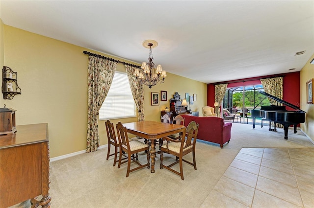 dining room with a chandelier, light colored carpet, and baseboards