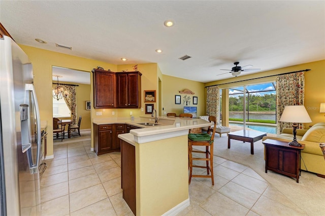 kitchen with open floor plan, a sink, a peninsula, a chandelier, and light tile patterned flooring