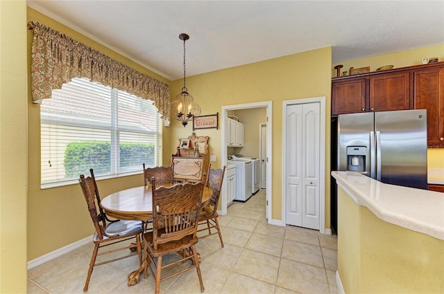 dining space featuring separate washer and dryer, a chandelier, light tile patterned flooring, and baseboards