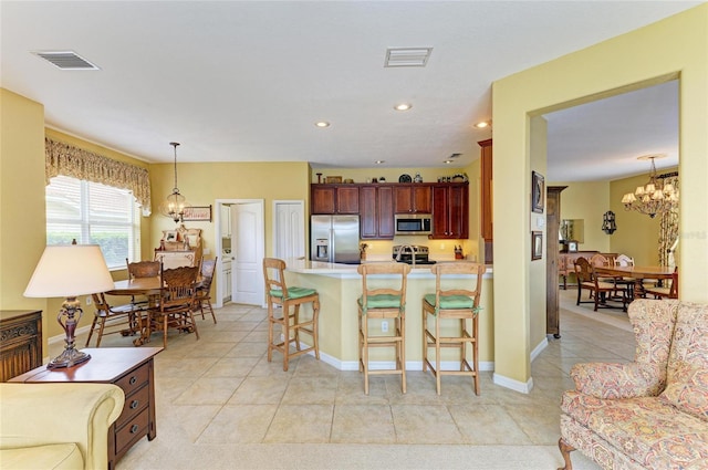 kitchen with appliances with stainless steel finishes, a chandelier, a kitchen breakfast bar, a peninsula, and hanging light fixtures