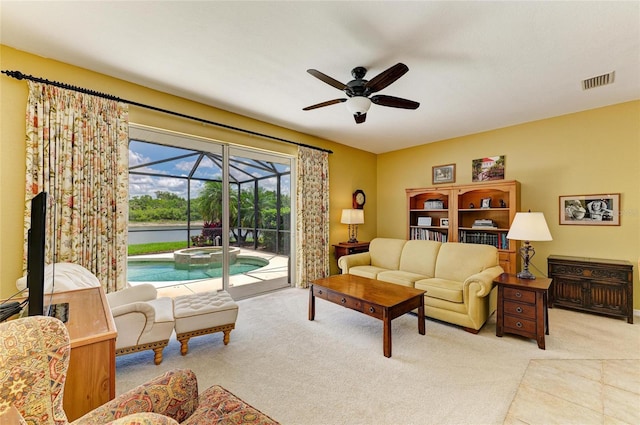 living area featuring a sunroom, a ceiling fan, and light colored carpet