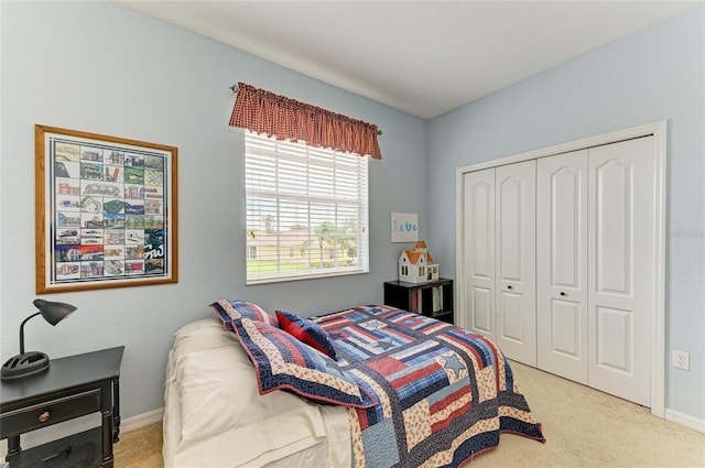 carpeted bedroom with a closet and baseboards