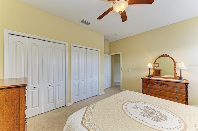 carpeted bedroom featuring two closets, ceiling fan, and baseboards