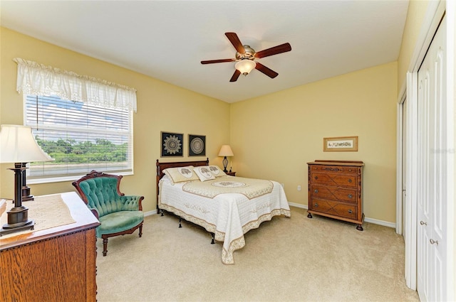 bedroom featuring a closet, light colored carpet, baseboards, and ceiling fan
