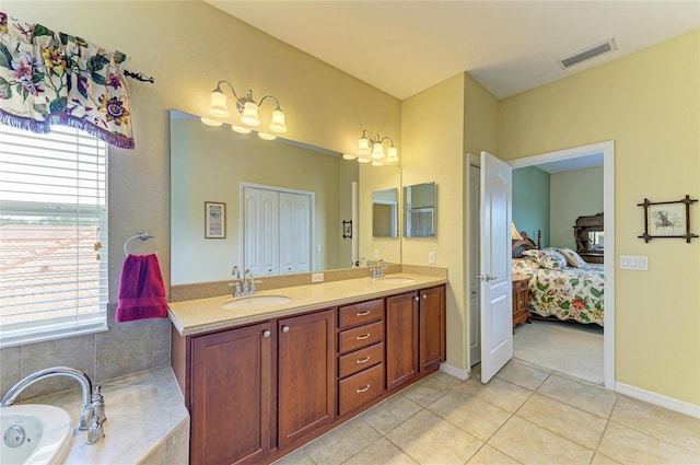 full bathroom with tile patterned flooring, ensuite bath, double vanity, a tub, and baseboards