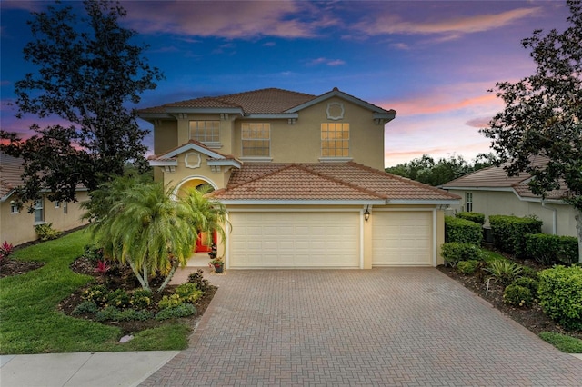 mediterranean / spanish house featuring a tiled roof, stucco siding, and driveway