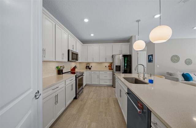 6185 SW 89th Ct, Ocala, FL 34481 - kitchen with appliances with stainless steel finishes, a sink, light wood-style floors, white cabinets, and light countertops