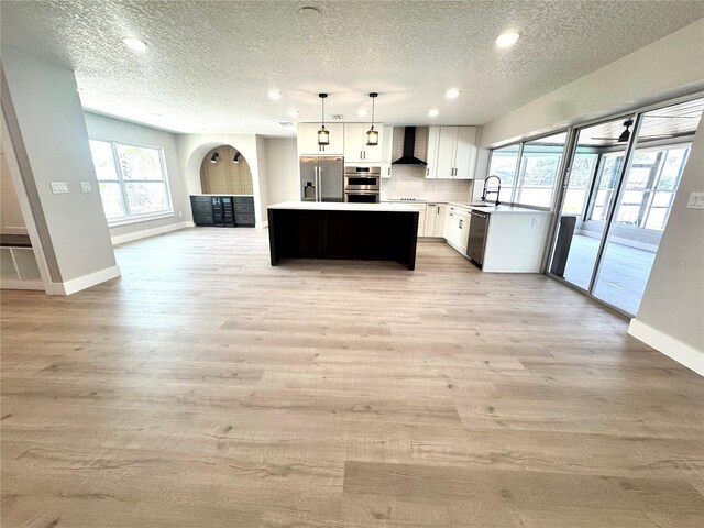 6524 Senegal Palm Way, Apollo Beach, FL 33572 - kitchen with appliances with stainless steel finishes, wall chimney range hood, a textured ceiling, open floor plan, and a sink