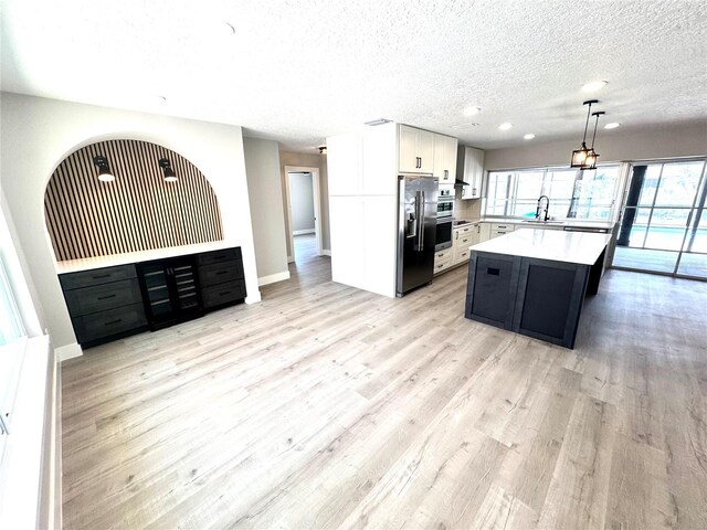 6524 Senegal Palm Way, Apollo Beach, FL 33572 - kitchen with stainless steel appliances, light countertops, a textured ceiling, light wood finished floors, and recessed lighting