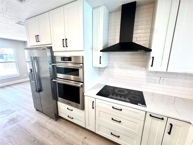 6524 Senegal Palm Way, Apollo Beach, FL 33572 - kitchen with wall chimney exhaust hood, a textured ceiling, appliances with stainless steel finishes, white cabinets, and light wood-style flooring