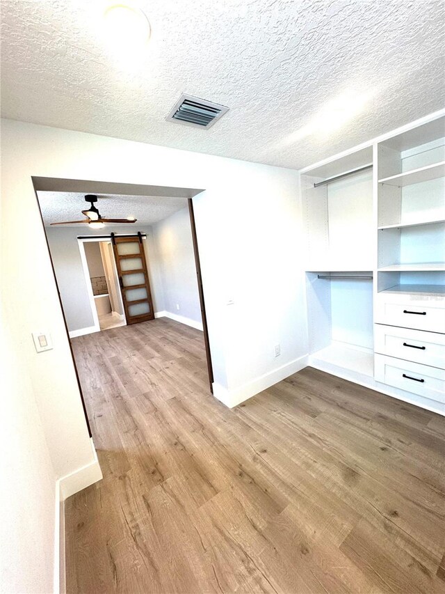 6524 Senegal Palm Way, Apollo Beach, FL 33572 - empty room featuring light wood-type flooring, a barn door, baseboards, and a textured ceiling