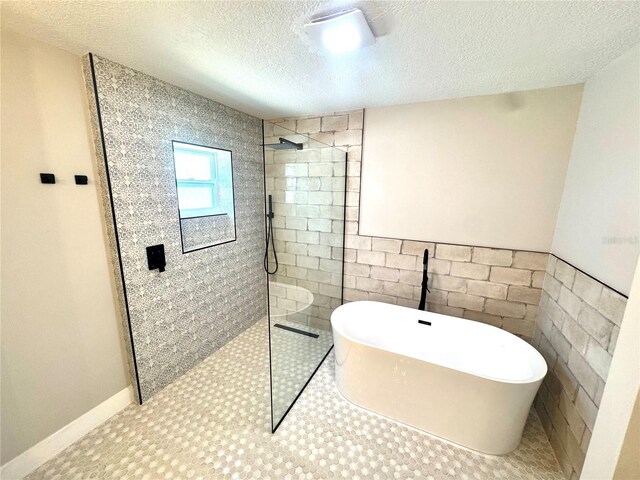 6524 Senegal Palm Way, Apollo Beach, FL 33572 - bathroom featuring a walk in shower, a textured ceiling, a soaking tub, tile walls, and a wainscoted wall