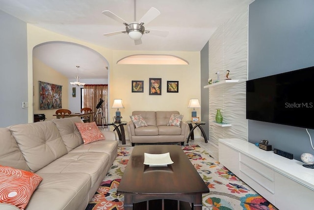 living area featuring a chandelier, a ceiling fan, and arched walkways
