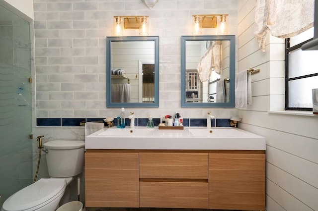 full bath with double vanity, toilet, and tile walls