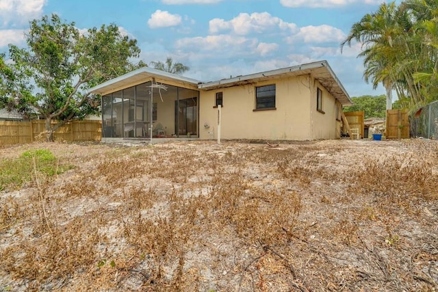 rear view of property featuring a sunroom and stucco siding