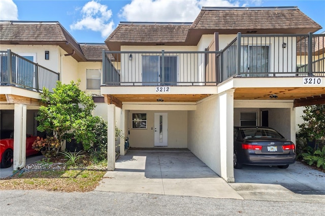 3212 Ramblewood Dr N Unit 3212, Sarasota, FL 34237 - view of front of home with mansard roof, a carport, stucco siding, a balcony, and concrete driveway