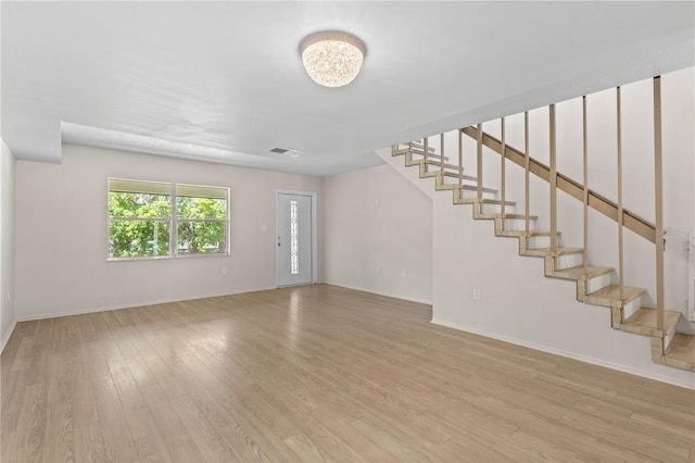 3212 Ramblewood Dr N Unit 3212, Sarasota, FL 34237 - unfurnished living room featuring stairs, light wood-style floors, and baseboards