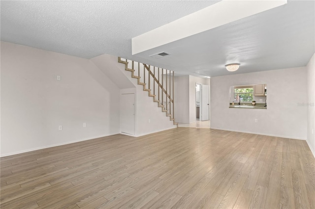3212 Ramblewood Dr N Unit 3212, Sarasota, FL 34237 - unfurnished living room with stairway, light wood-type flooring, and baseboards